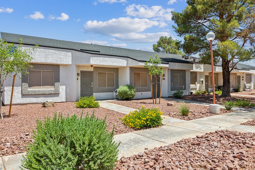 an exterior view of a white building with a sidewalk and plants