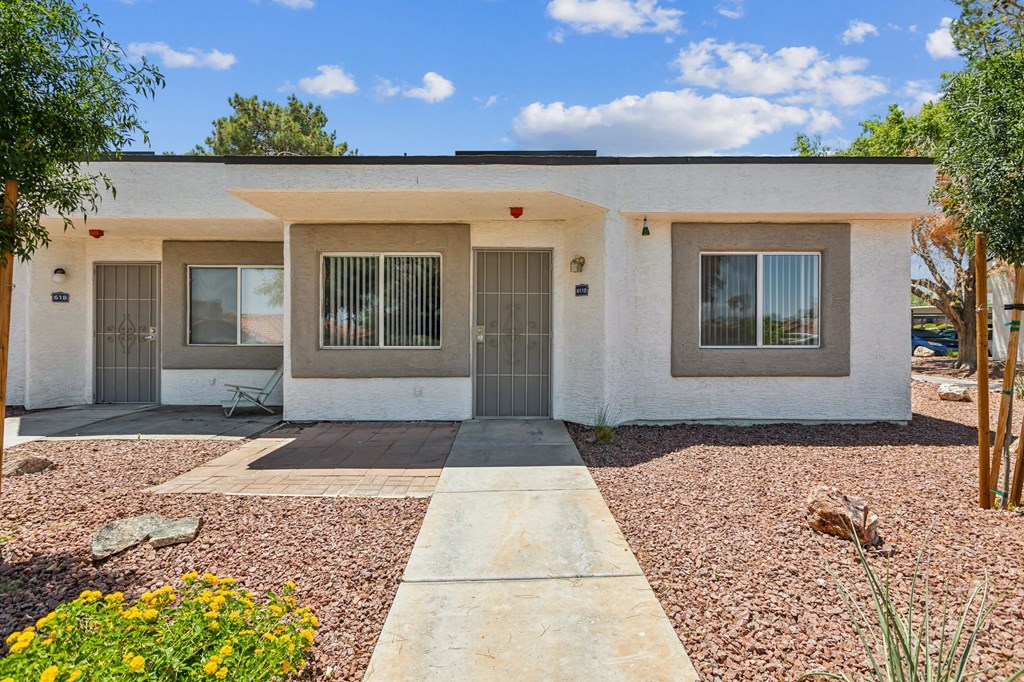 a white house with two doors and a gravel driveway