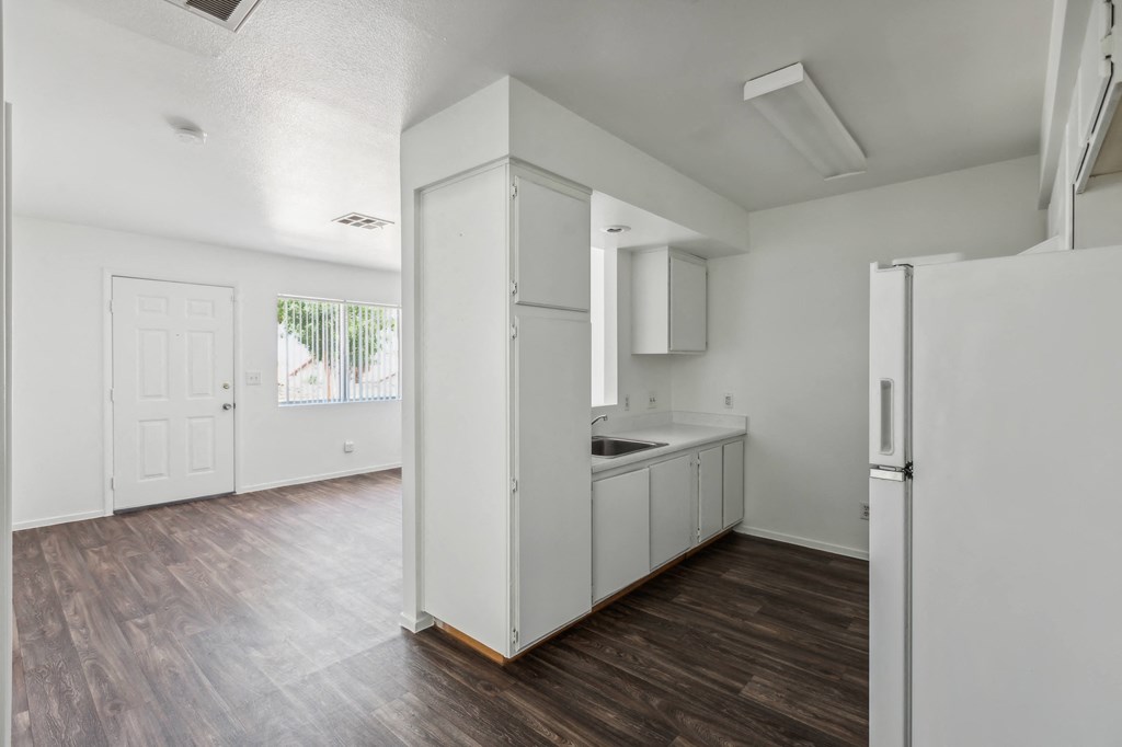 an empty kitchen with white cabinets and a white refrigerator