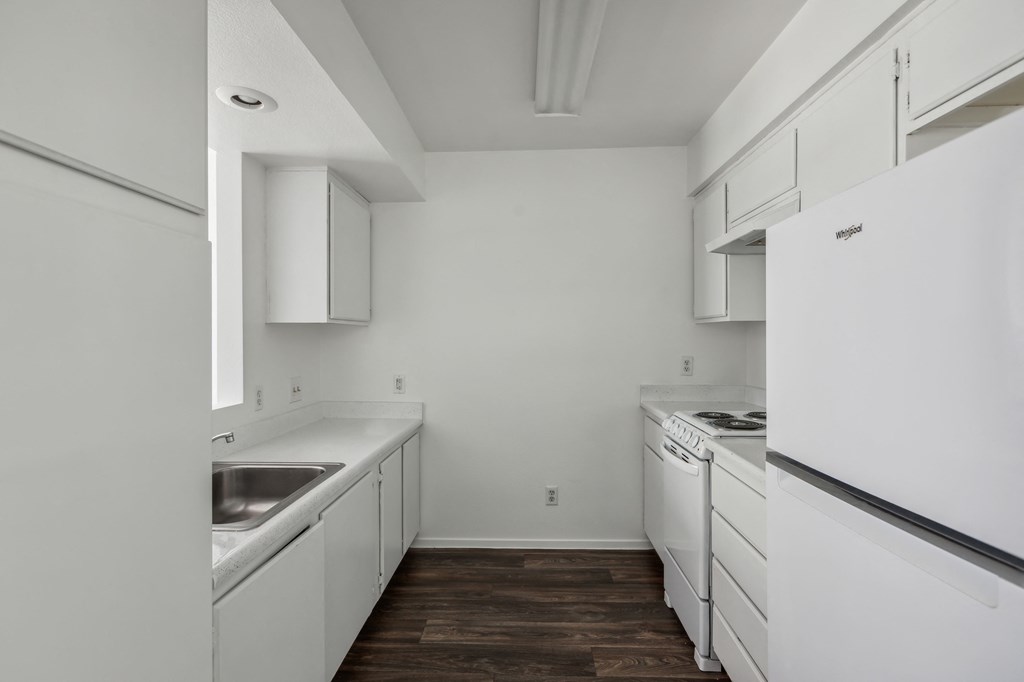 a kitchen with white cabinets and white appliances and a stainless steel sink