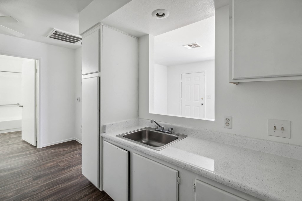 a kitchen with white cabinets and a stainless steel sink