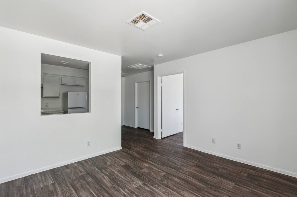 a living room with white walls and wood flooring and a large mirror