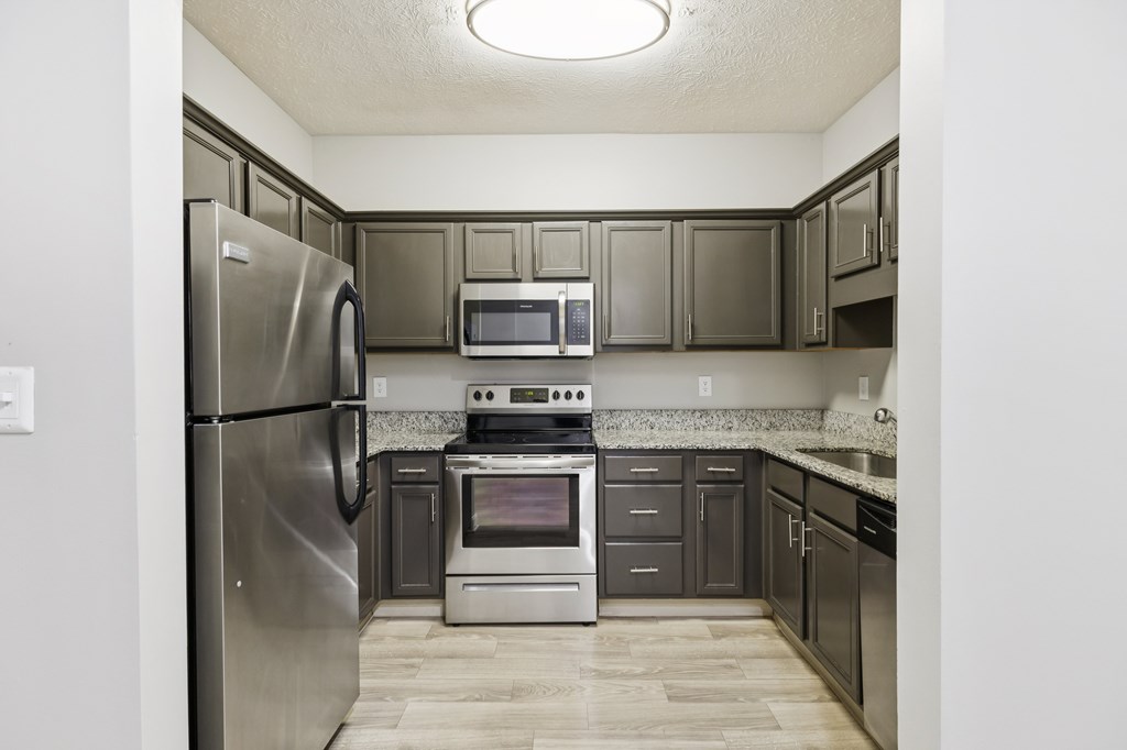 A kitchen with a stainless steel refrigerator, microwave, oven, and cabinets.
