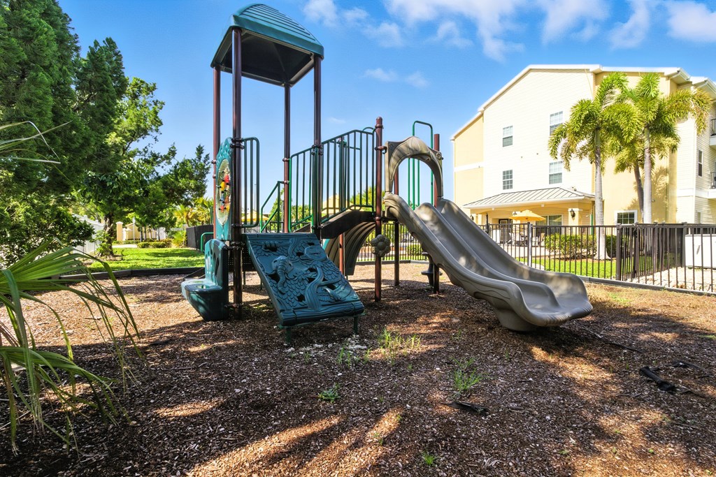 A playground with a green slide and a grey slide.