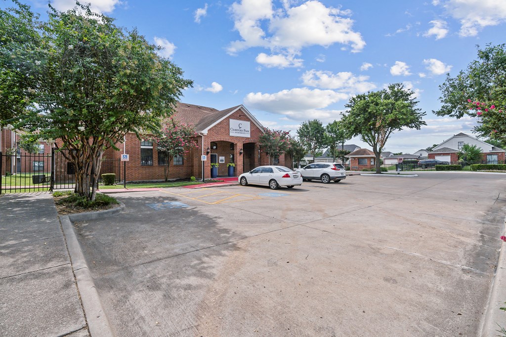 a parking lot in front of a brick building with cars parked in front
