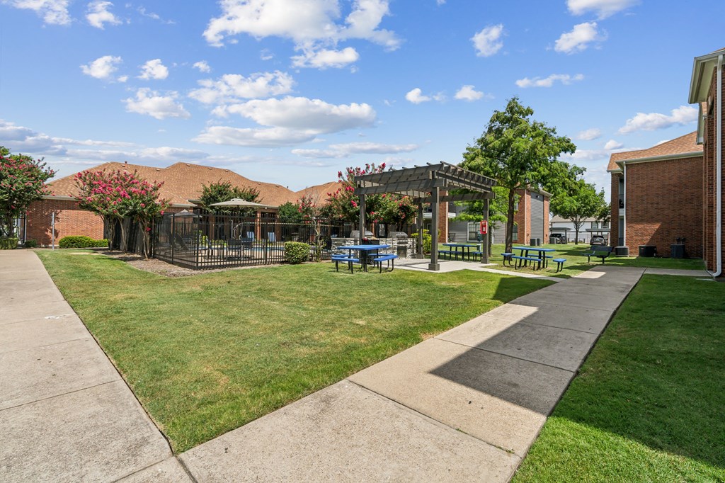 a yard with picnic tables and a gazebo in front of a building
