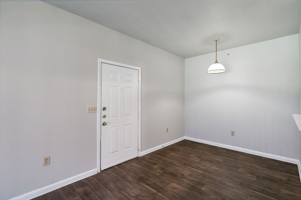 a bedroom with white walls and wood flooring and a white door