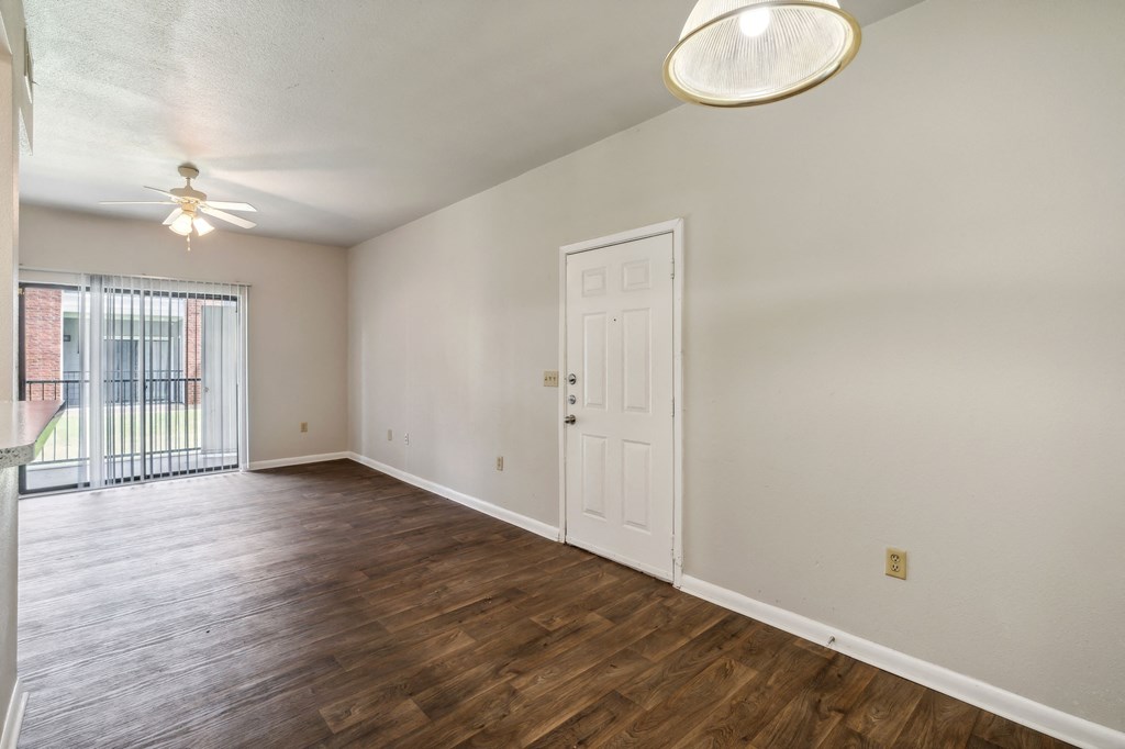 an empty living room with wood flooring and a door to a balcony