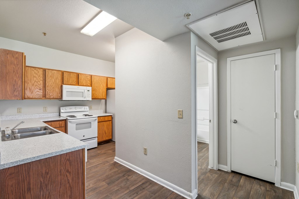 an empty kitchen with white appliances and wooden cabinets