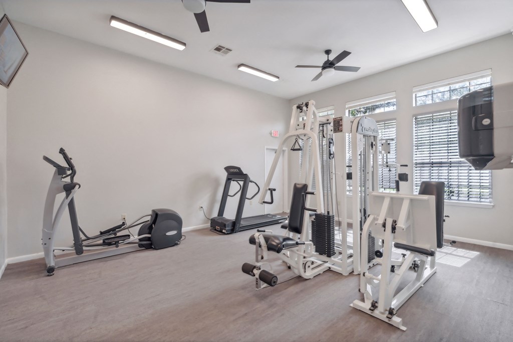 a gym with weights and cardio equipment and a window