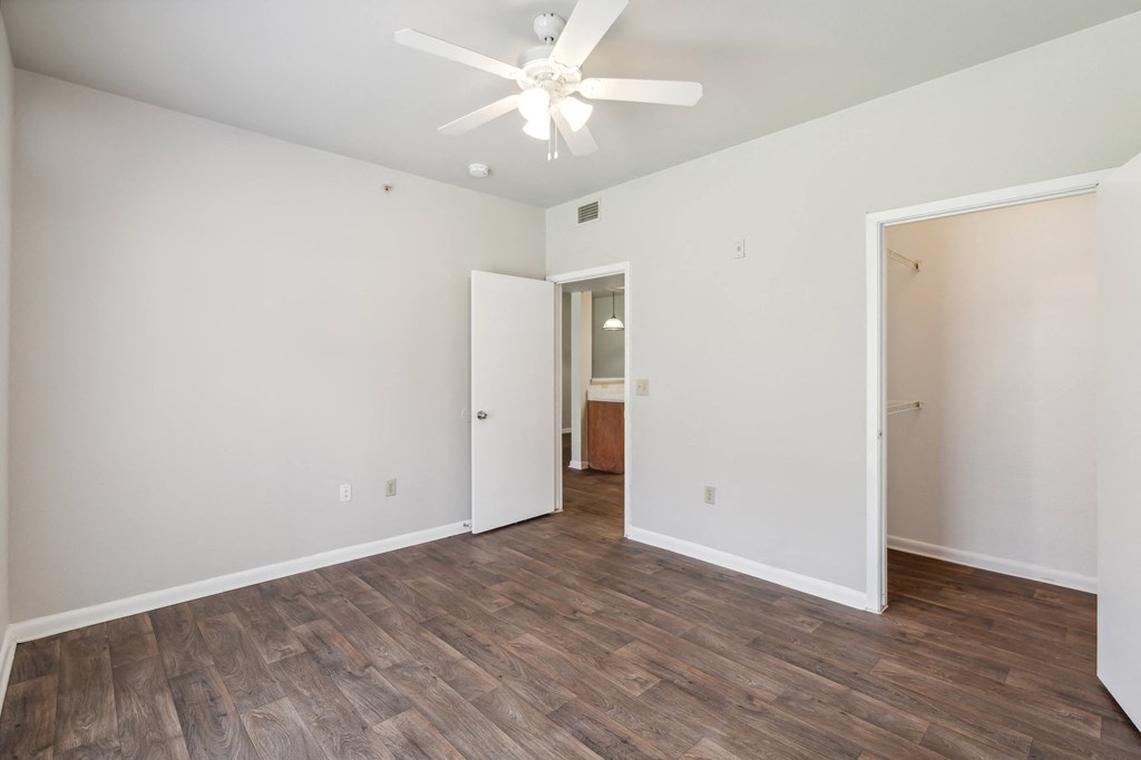 an empty living room with white walls and a ceiling fan