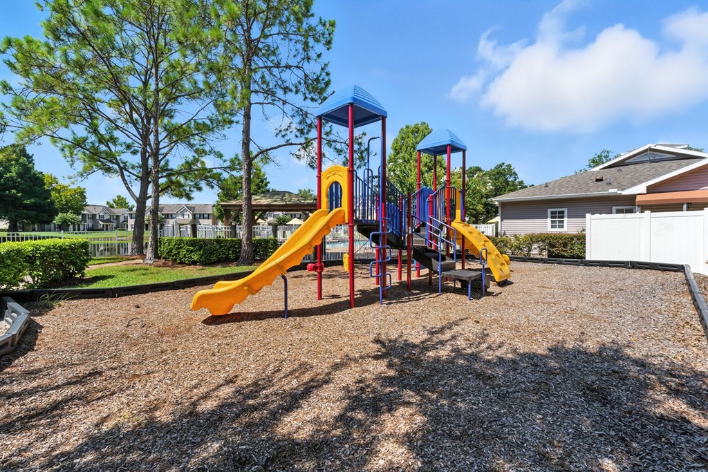 A playground with a yellow slide and a blue and red structure.