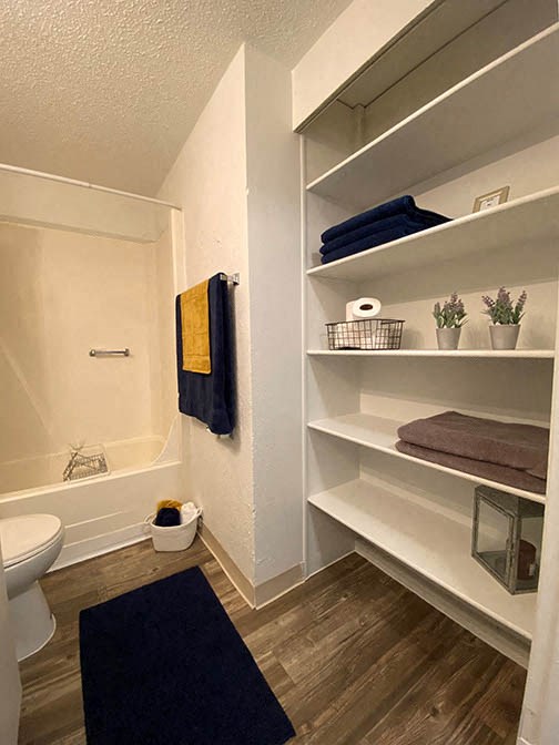 a bathroom with a toilet and a bath tub and shelves