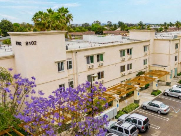 the view of a building from a balcony with purple flowers