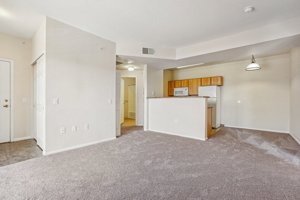 A spacious living room with a kitchenette in the background. at Stetson Meadows Apartments, Colorado Springs, Colorado