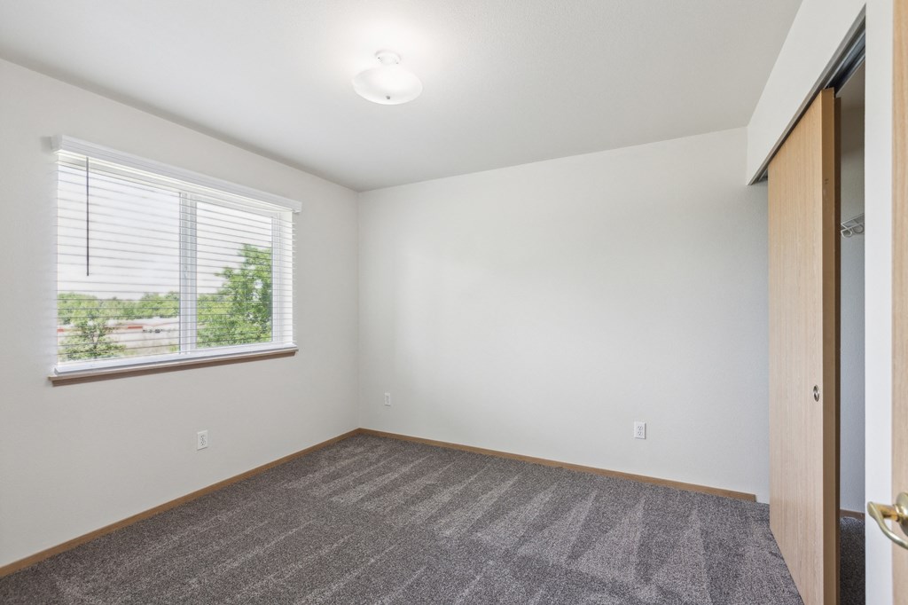 an empty living room with a large window and a carpet