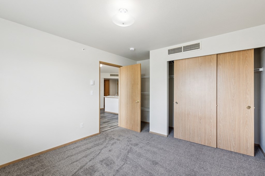a living room with white walls and a door to a closet