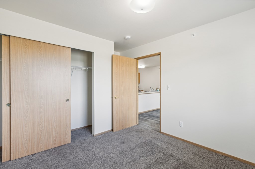 a bedroom with a door to a closet and a bathroom