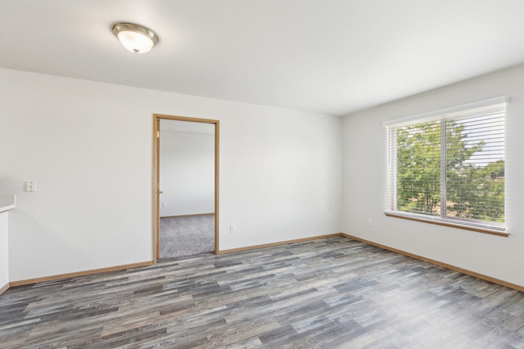 an empty living room with wood floors and a window