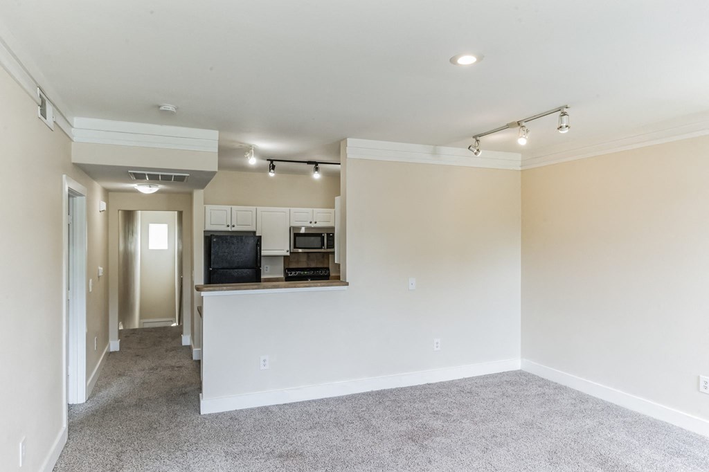 a renovated living room and kitchen with white walls and a carpet floor at Province of Briarcliff Apartments, Kansas City, 64118