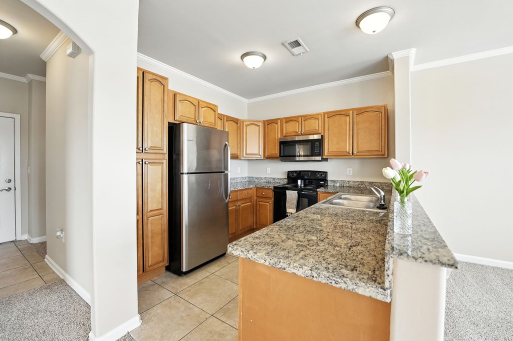 A kitchen with a granite countertop and wooden cabinets.