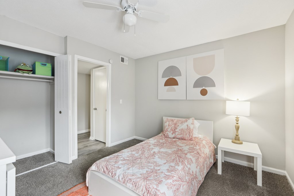 A bedroom with a bed, nightstand, and a ceiling fan.