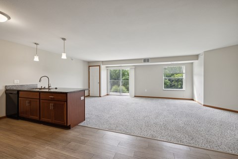 an empty living room and kitchen with wood flooring and a window