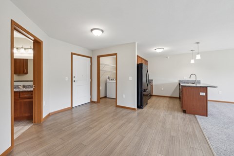 a kitchen and living room with wood flooring and a refrigerator and a sink