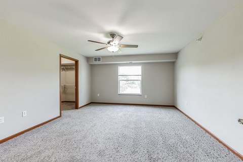 an empty living room with a ceiling fan and a window