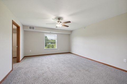 an empty living room with a ceiling fan and a window