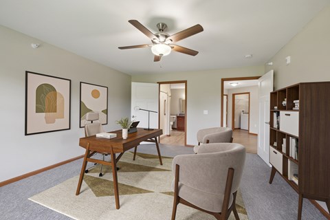 A room with a ceiling fan and a desk with a chair.