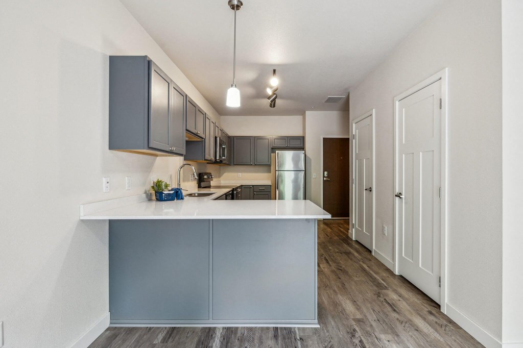 an open kitchen and living room with a white counter top and blue cabinets an open kitchen and living room with a white counter top and blue cabinets at Lake Ridge, Prior Lake, MN, 55379