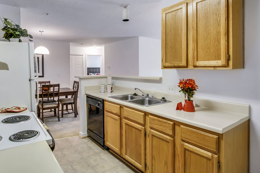 a kitchen with white counters and wooden cabinets and a sink
