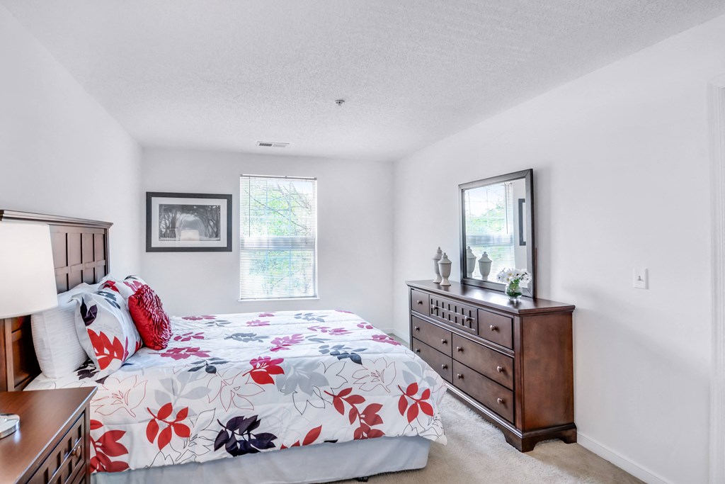 a bedroom with a bed and dresser and a window