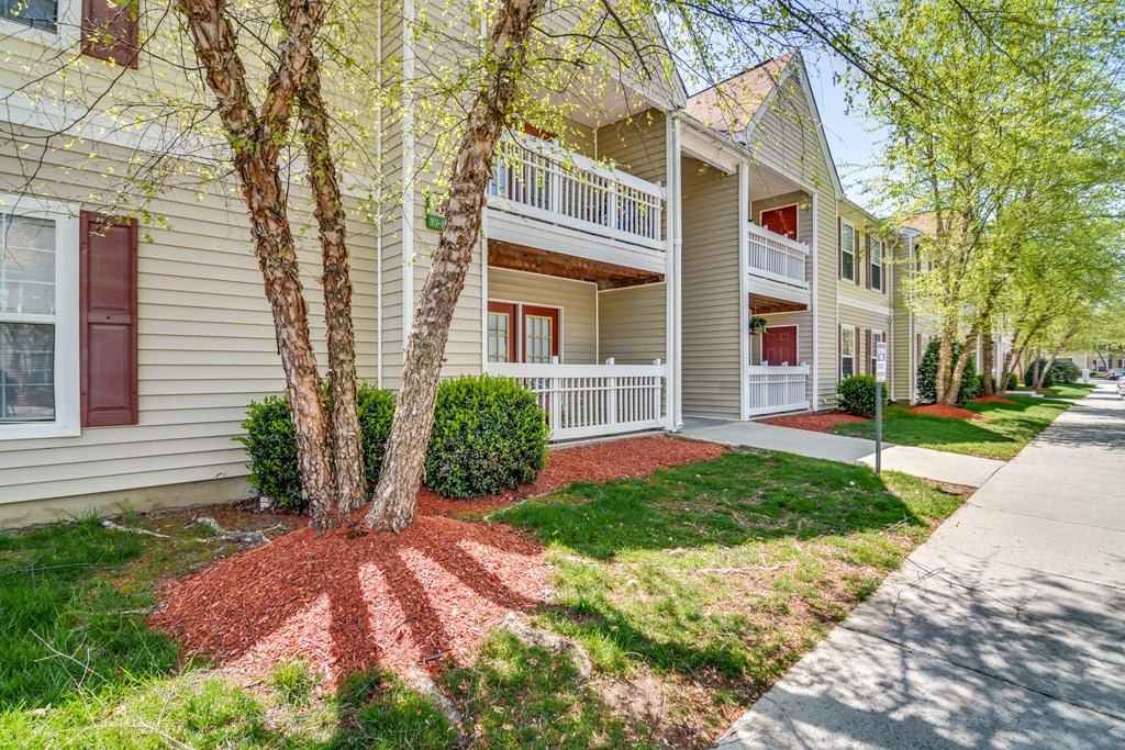 a white house with trees and a sidewalk in front of it