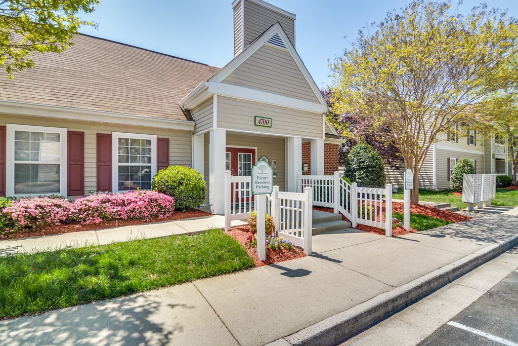 a small white house with a porch and a sidewalk in front of it