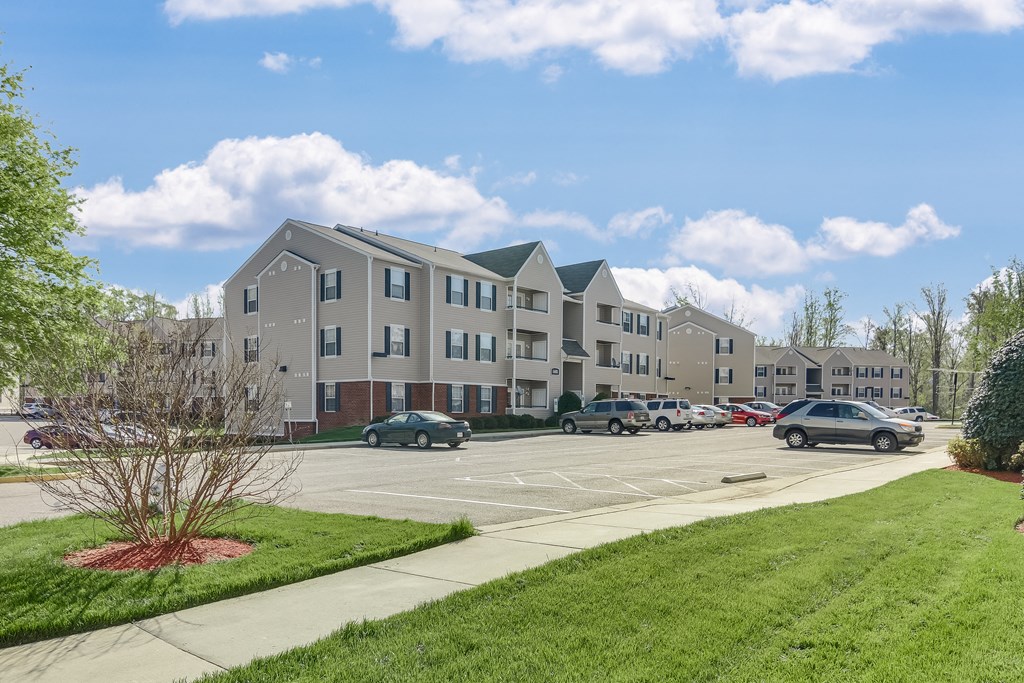 a parking lot with cars in front of an apartment building