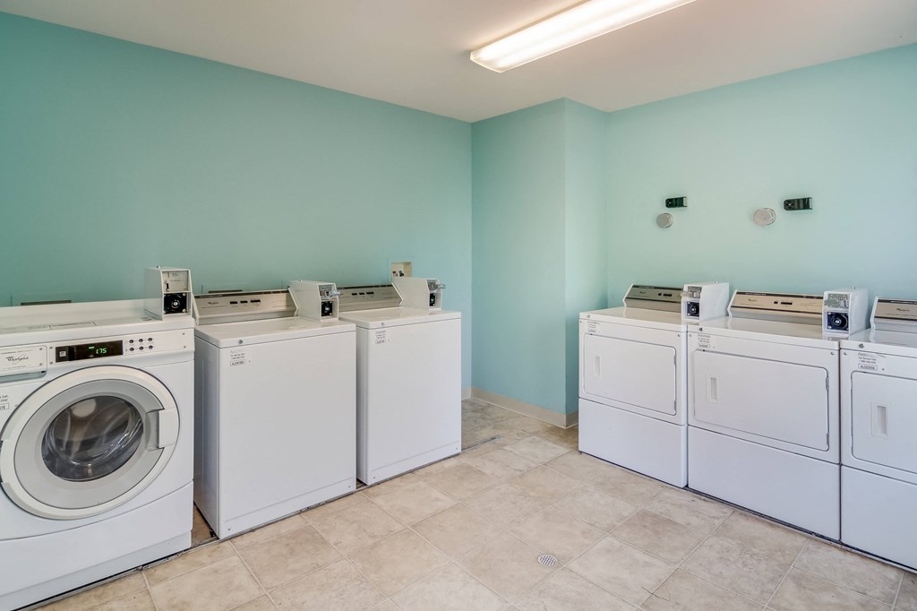 a group of washes and dryers in a laundry room with a blue wall