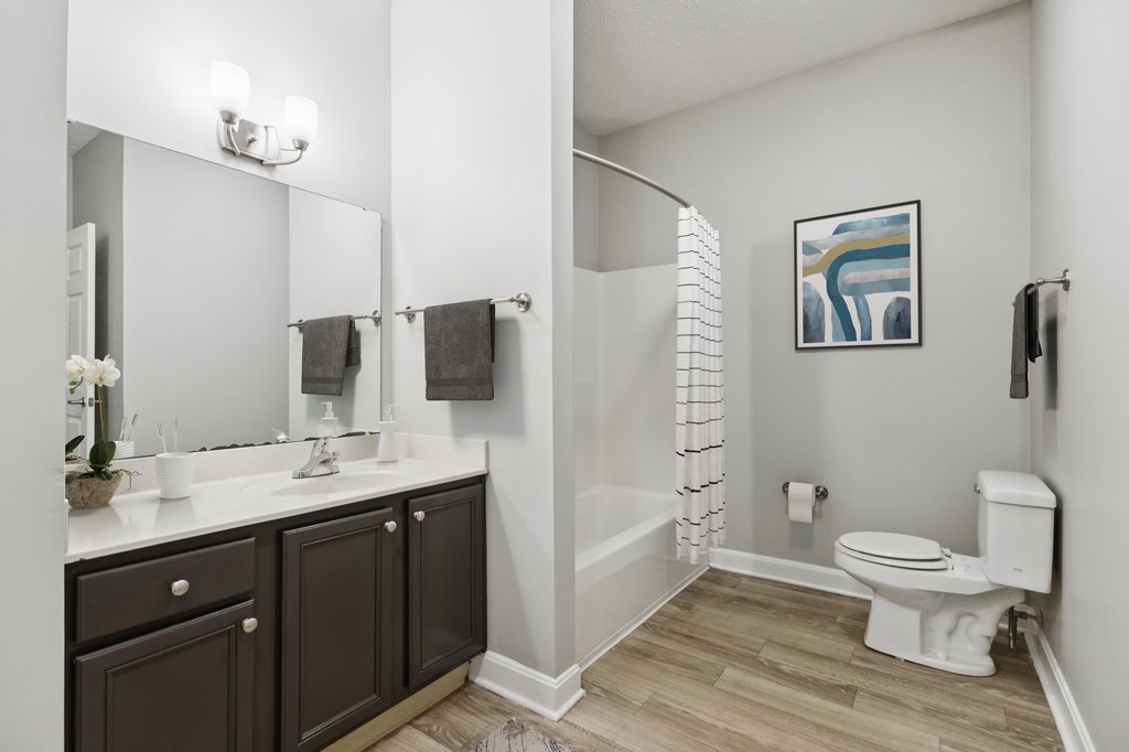 A bathroom with a toilet, sink, and mirror.