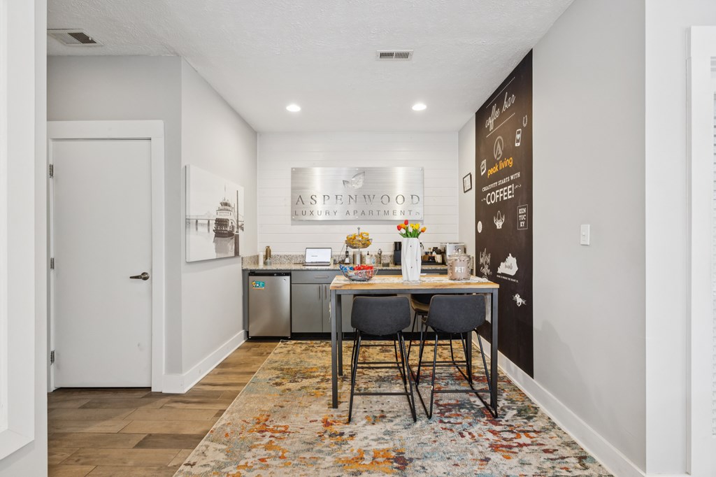 A kitchen area with a table and chairs in front of a chalkboard wall.
