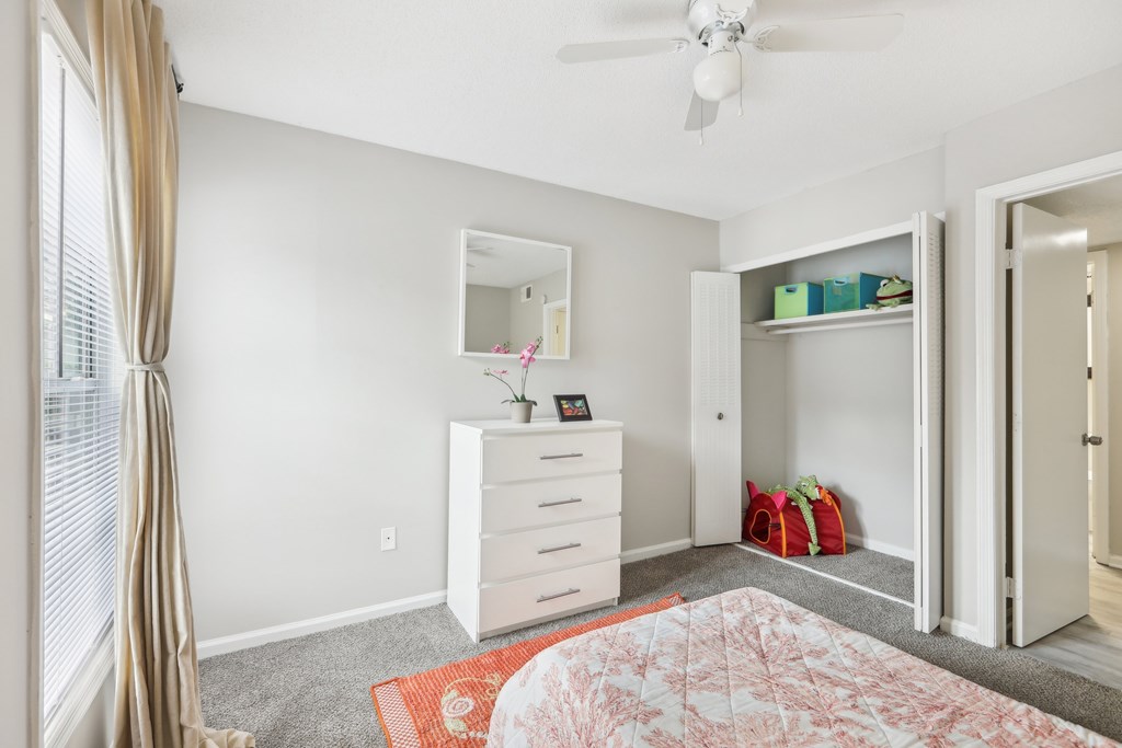 A bedroom with a dresser, mirror, and a ceiling fan.