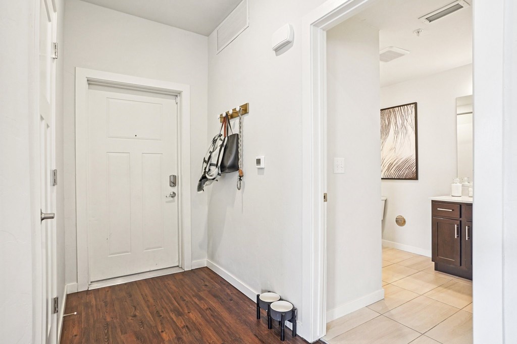 A hallway with a white door and a coat rack with several coats hanging on it. at Connect at First Creek Apartments, Colorado, 80249