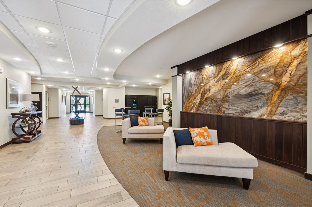 a lobby with couches and chairs and a large painting on the wall