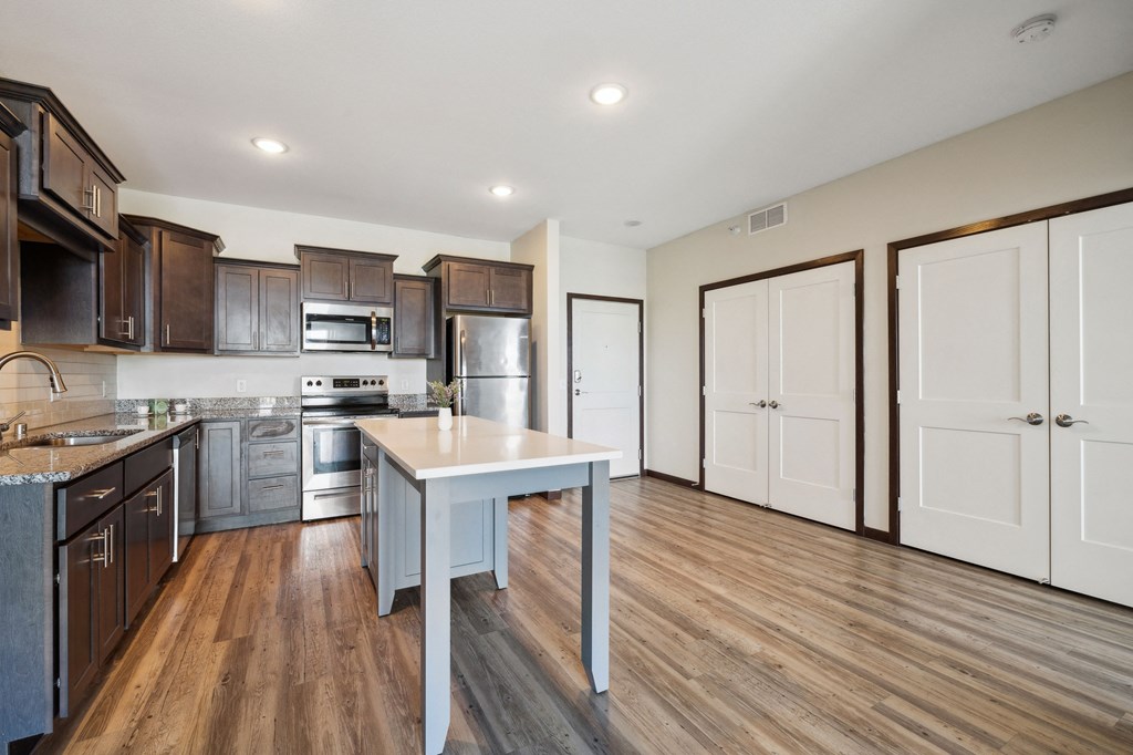 an open kitchen with wood flooring and stainless steel appliances