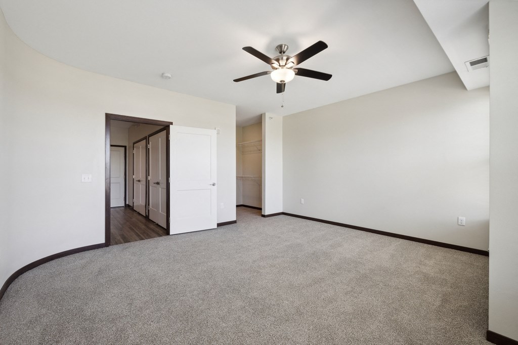 an empty living room with a ceiling fan and white walls