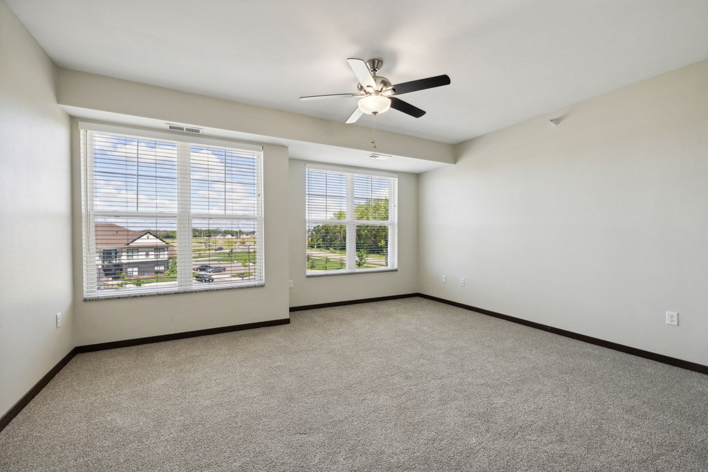 the living room of a home with large windows and a ceiling fan
