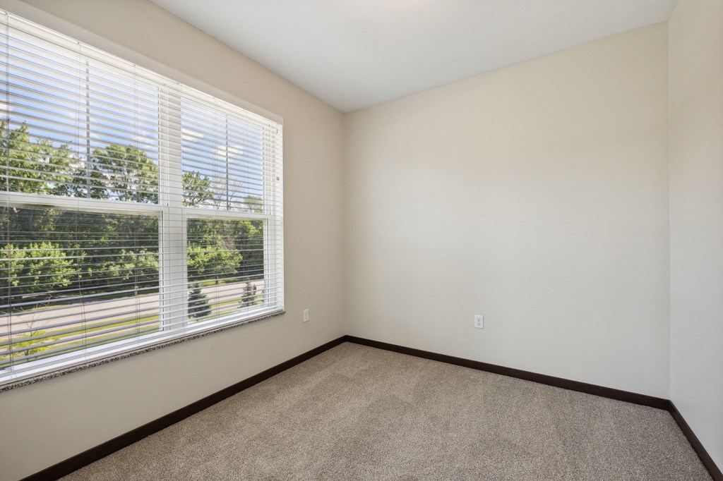 an empty bedroom with a large window and carpeting