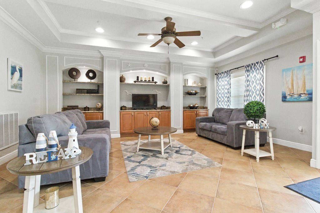 A living room with a grey couch, a coffee table, and a ceiling fan.