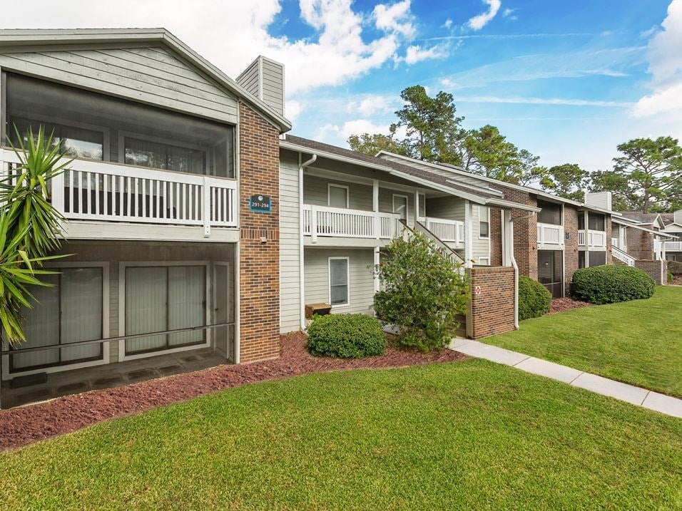 an apartment building with balconies and a grass yard