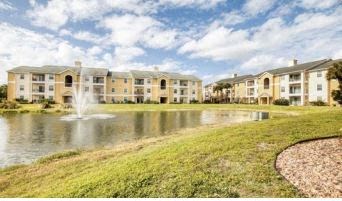 a pond with a fountain in the middle of an apartment complex